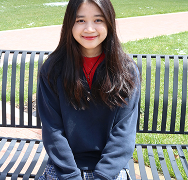 Happy student sitting outside wearing school uniform